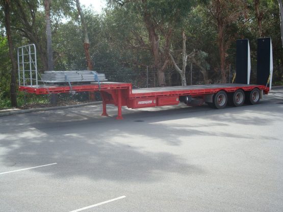 drop deck trailer not hooked onto truck in red standing in parking lot in front of gumtrees.